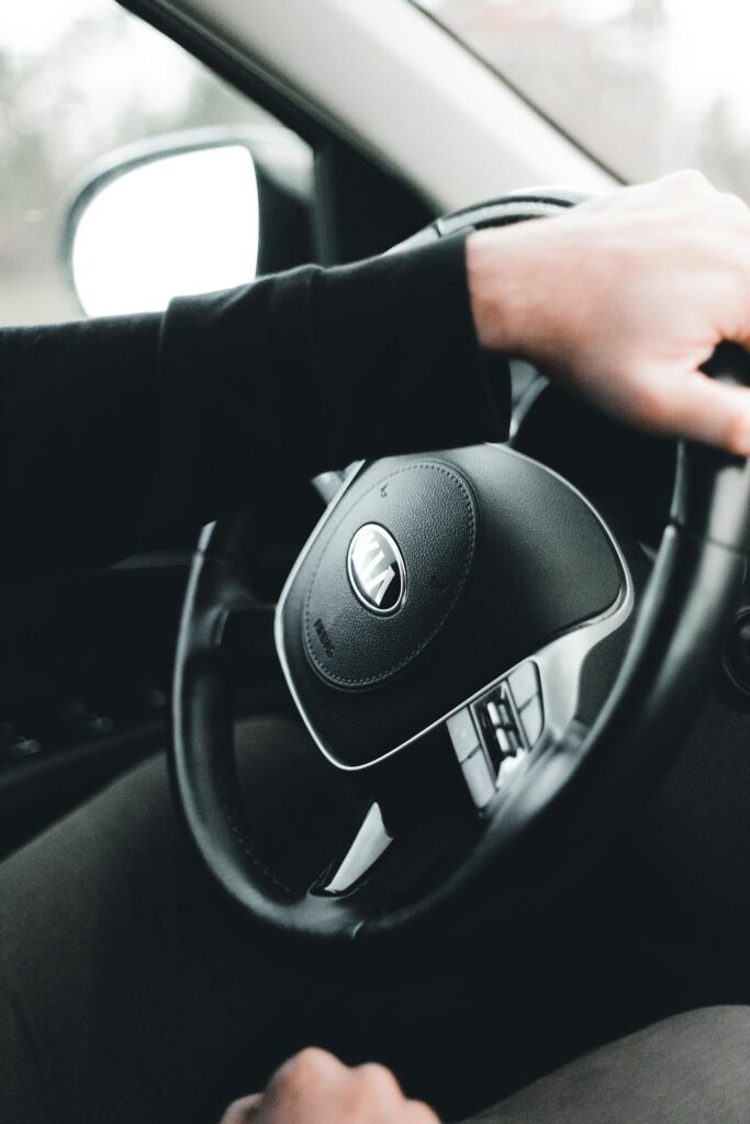 Close-up of hands gripping a car steering wheel, showcasing driving and control.