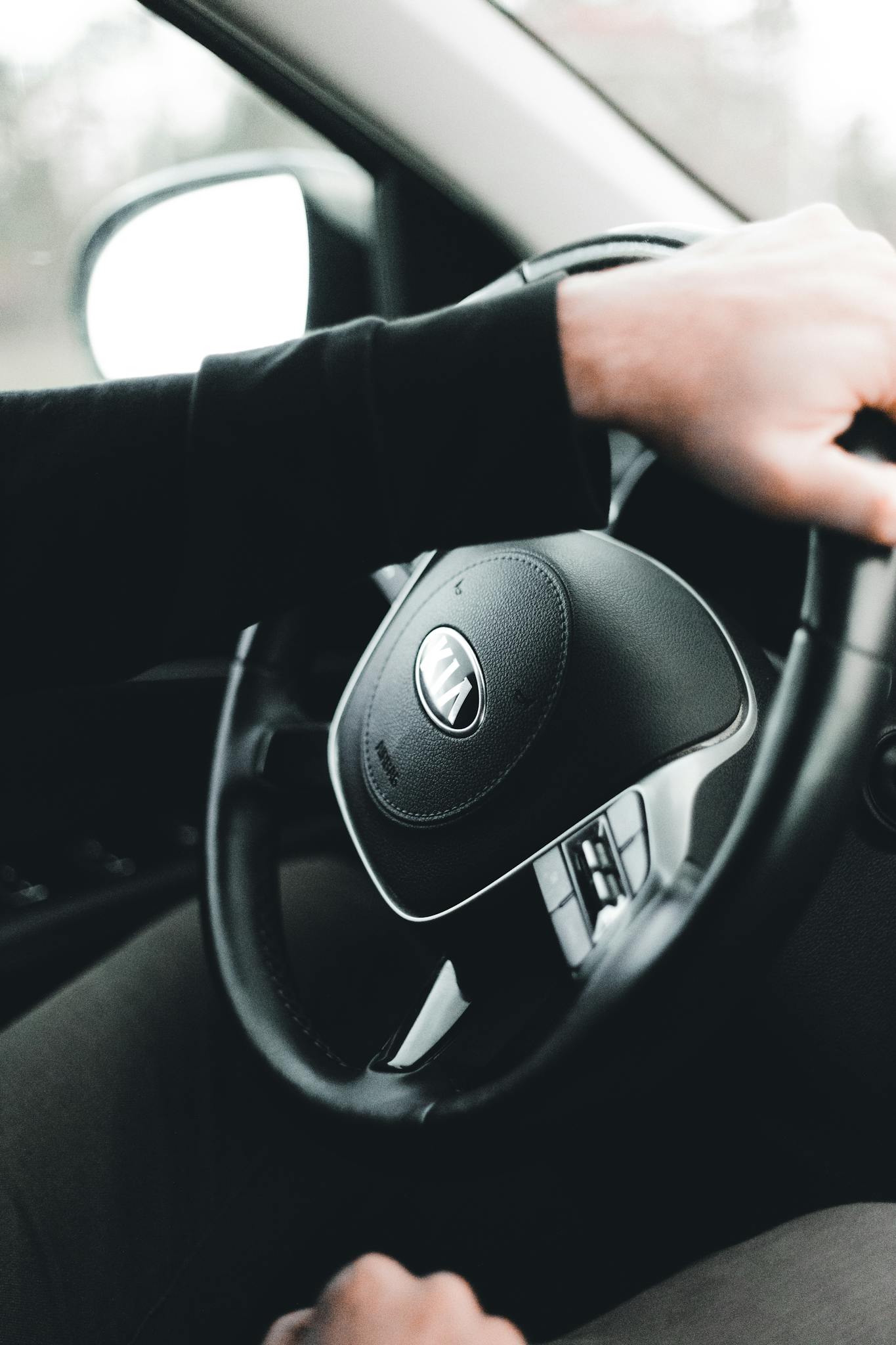 Close-up of hands gripping a car steering wheel, showcasing driving and control.